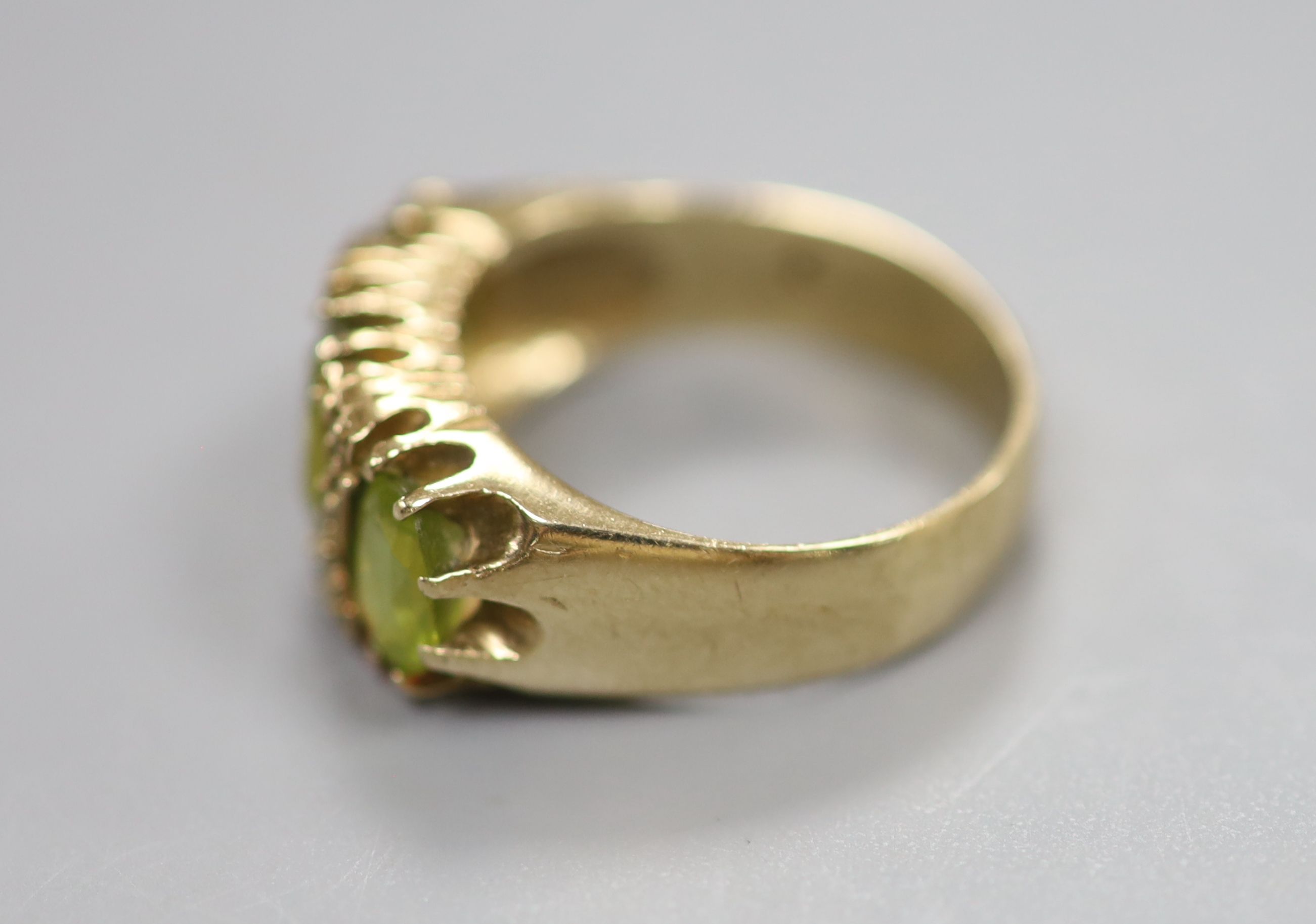 A modern 9ct gold, three stone peridot and diamond chip set dress ring, size P, gross 6 grams.